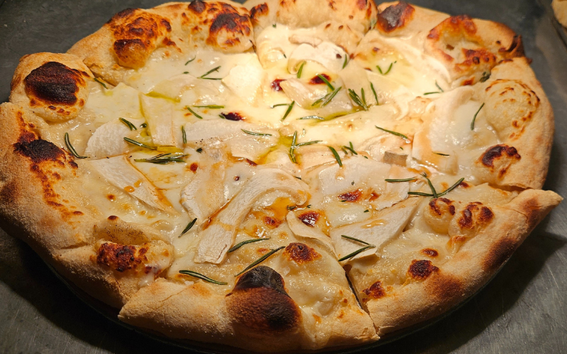 A freshly baked pizza with a crisp crust, herbs and nebrodini mushroom pieces on top.